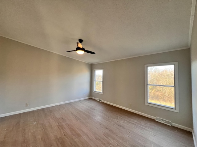 unfurnished room with ornamental molding, light wood-type flooring, visible vents, and baseboards