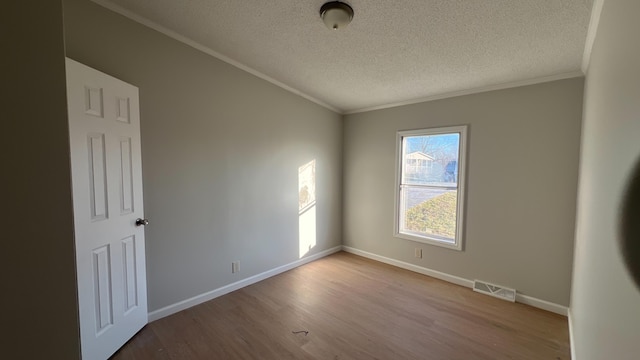 empty room with light wood-type flooring, baseboards, visible vents, and ornamental molding