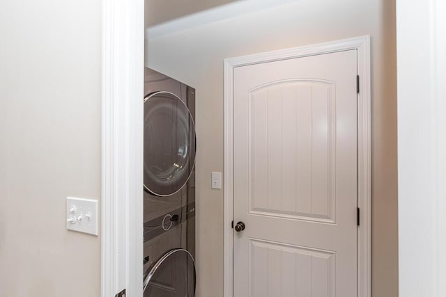 clothes washing area with stacked washer and dryer and laundry area