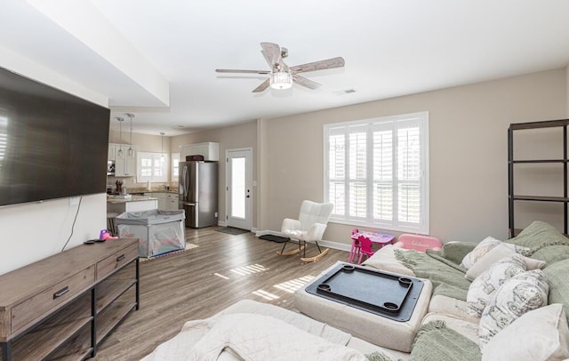 living room featuring visible vents, wood finished floors, a ceiling fan, and baseboards