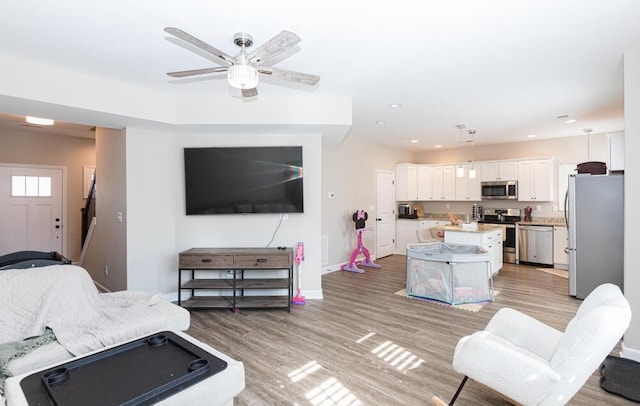 living room with a ceiling fan, light wood-type flooring, baseboards, and recessed lighting