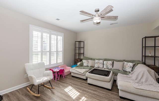 living area featuring a ceiling fan, wood finished floors, visible vents, and baseboards