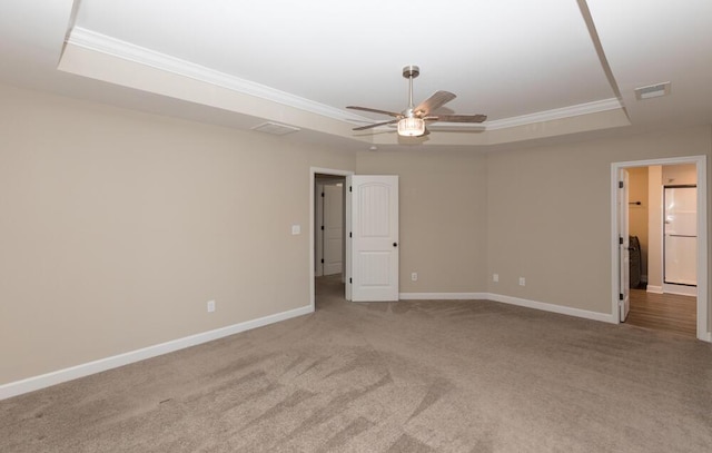 spare room with baseboards, visible vents, ornamental molding, a tray ceiling, and carpet flooring