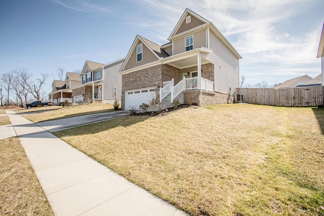 craftsman inspired home featuring covered porch, fence, driveway, and a front lawn