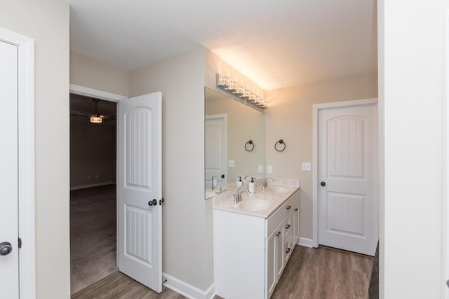 full bath with double vanity, a sink, and wood finished floors