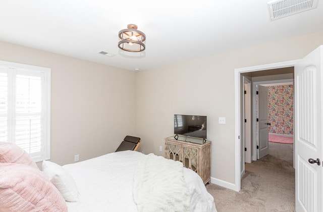 bedroom with baseboards, visible vents, and light colored carpet