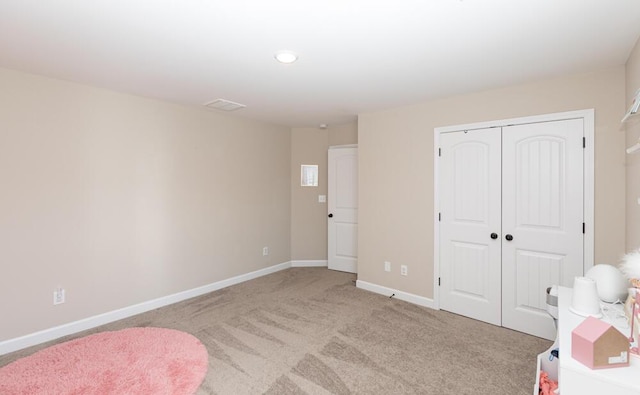 bedroom featuring baseboards, a closet, and light colored carpet