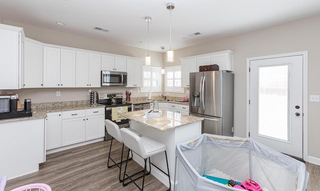 kitchen with appliances with stainless steel finishes, wood finished floors, and white cabinetry