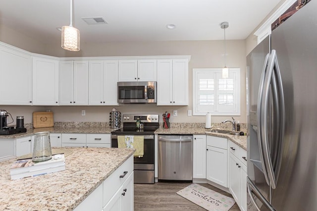 kitchen with visible vents, white cabinets, light wood-style flooring, appliances with stainless steel finishes, and a sink