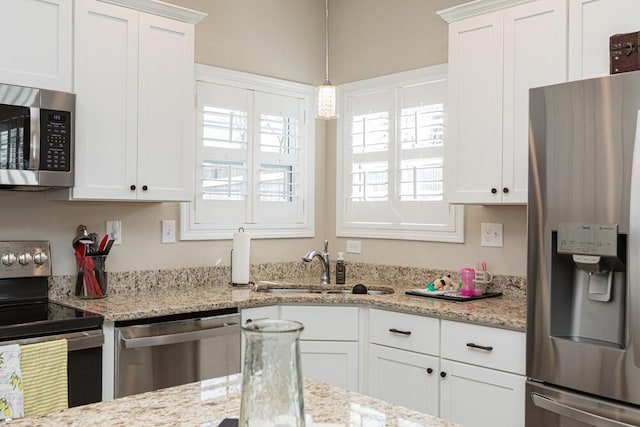 kitchen featuring white cabinets, pendant lighting, stainless steel appliances, and a sink