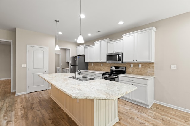 kitchen featuring stainless steel appliances, a sink, decorative backsplash, light wood finished floors, and an island with sink