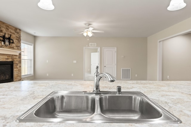 kitchen with a large fireplace, visible vents, light countertops, and a sink