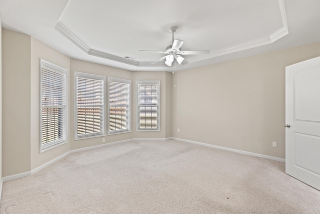 carpeted empty room with ceiling fan, baseboards, a raised ceiling, and crown molding