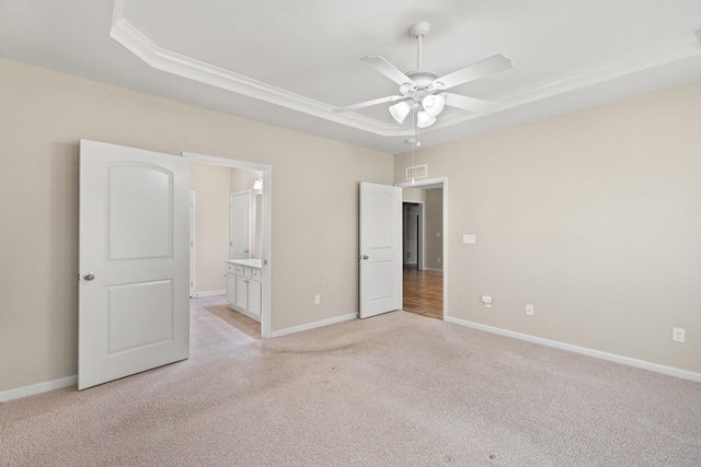 unfurnished bedroom featuring a raised ceiling, light colored carpet, visible vents, and baseboards