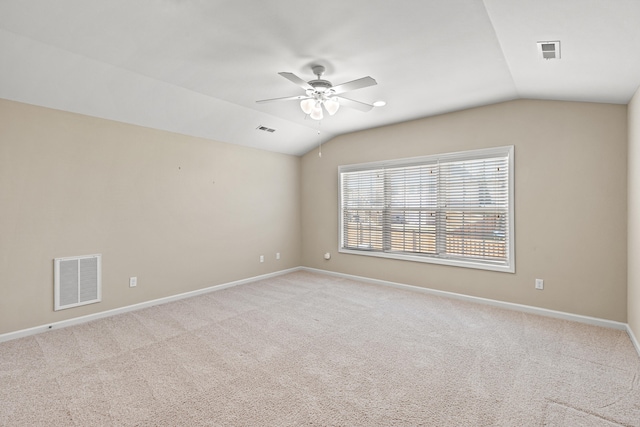 carpeted empty room featuring visible vents, vaulted ceiling, and baseboards