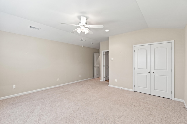 unfurnished bedroom with vaulted ceiling, light colored carpet, visible vents, and baseboards