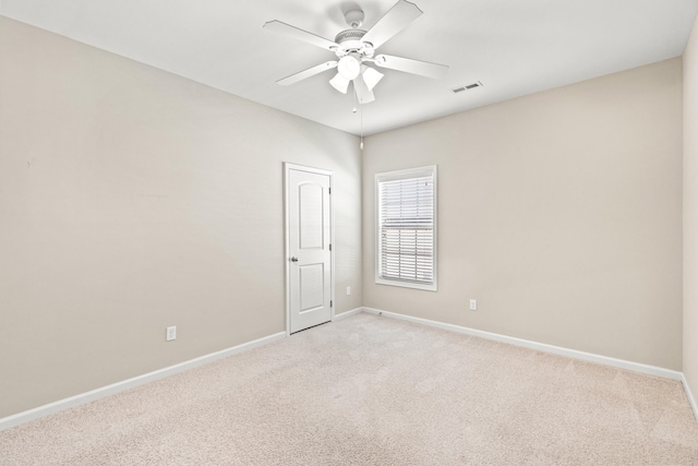 empty room featuring light carpet, ceiling fan, visible vents, and baseboards