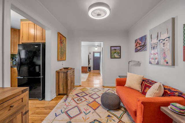 living room with ornamental molding, baseboards, and light wood finished floors