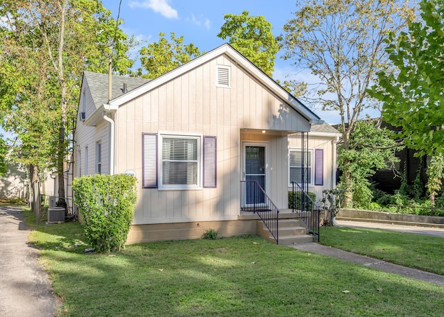 bungalow-style house featuring a front yard, roof with shingles, and cooling unit