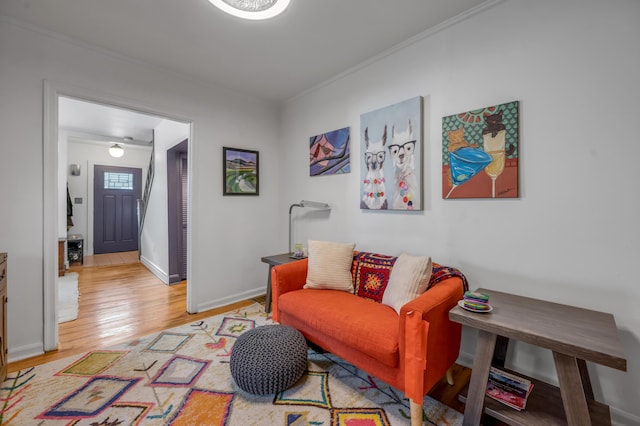 living area with crown molding, light wood-style flooring, and baseboards