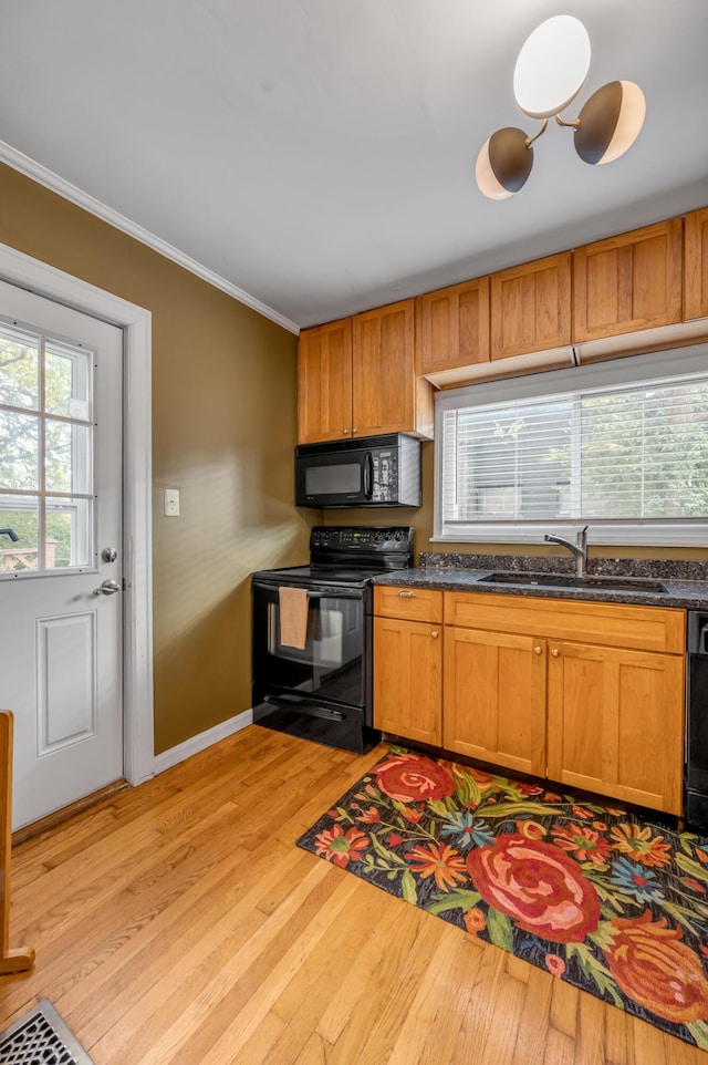 kitchen featuring a sink, light wood-style floors, brown cabinets, black appliances, and crown molding