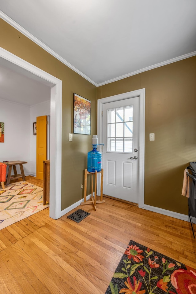 entryway with baseboards, light wood-type flooring, visible vents, and crown molding