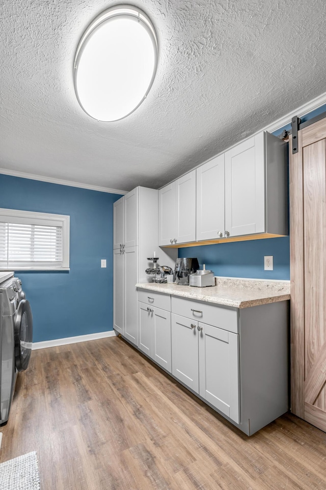 kitchen featuring light countertops, a barn door, light wood-style floors, white cabinetry, and independent washer and dryer