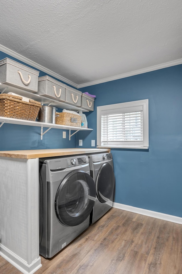 laundry room with laundry area, wood finished floors, baseboards, washer and dryer, and ornamental molding