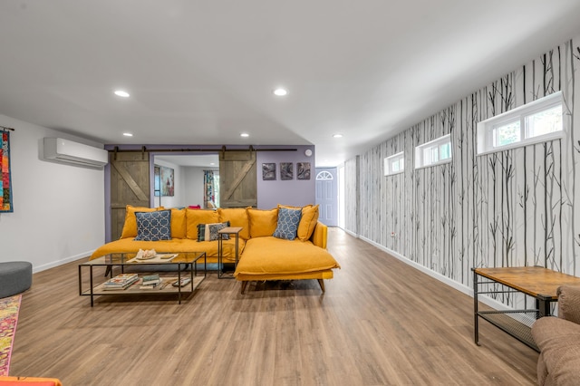 living room with a barn door, recessed lighting, baseboards, light wood finished floors, and a wall mounted air conditioner