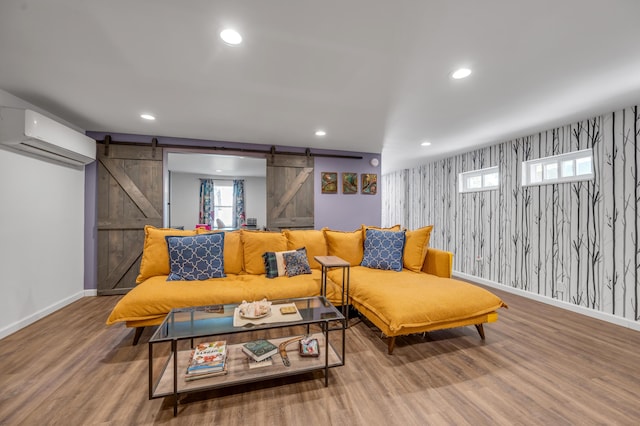 living room with a barn door, a wall mounted air conditioner, recessed lighting, and wallpapered walls