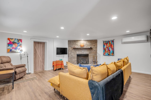 living area featuring recessed lighting, a wall mounted AC, a fireplace, and light wood-style floors