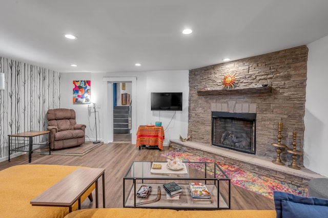 living area with recessed lighting, stairway, a stone fireplace, wood finished floors, and baseboards