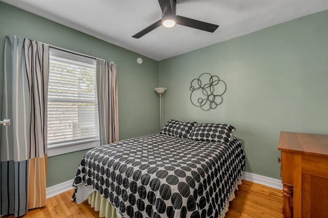 bedroom with a ceiling fan, light wood-style flooring, and baseboards