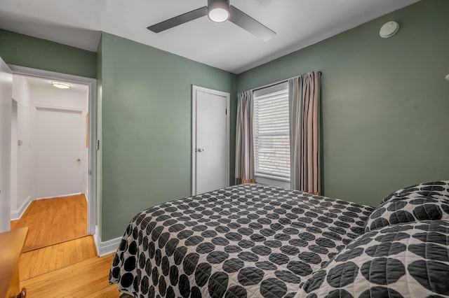 bedroom with light wood-style flooring, baseboards, and a ceiling fan