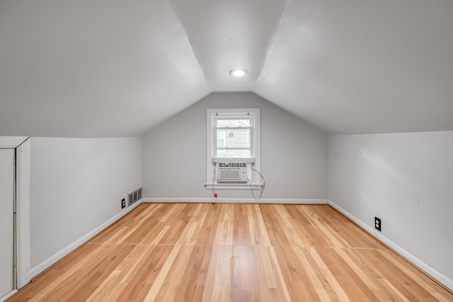 additional living space with lofted ceiling, visible vents, light wood-style floors, cooling unit, and baseboards