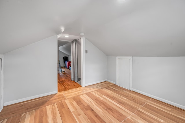 bonus room with lofted ceiling, light wood-type flooring, and baseboards