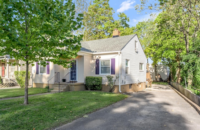 view of front facade with a shingled roof, fence, a chimney, and a front lawn