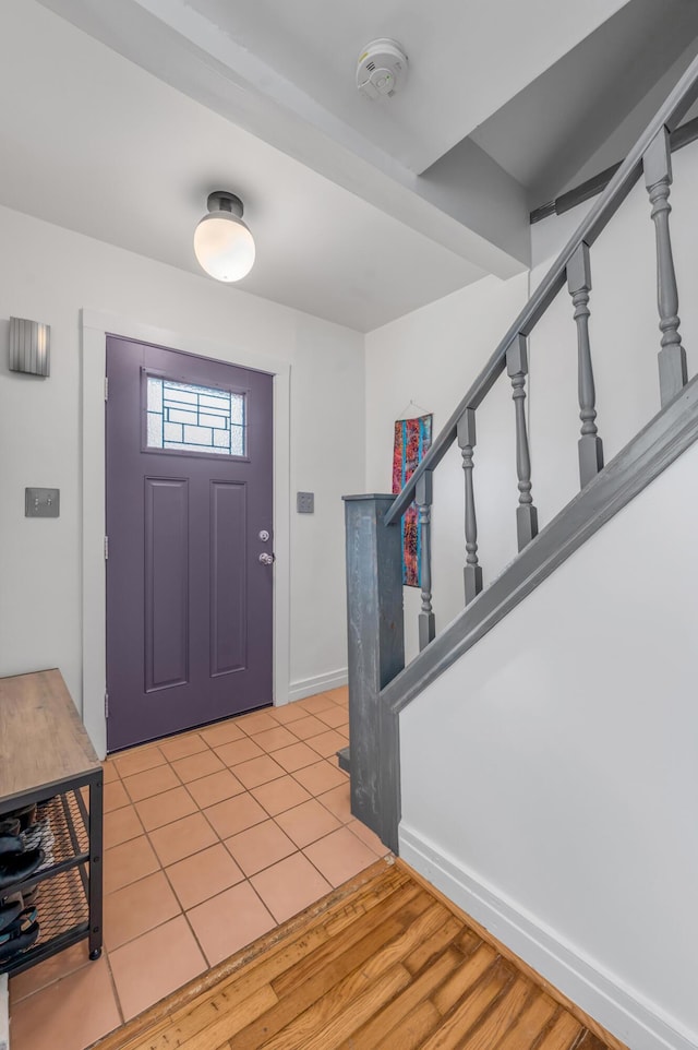 foyer entrance featuring stairway, baseboards, and light tile patterned floors