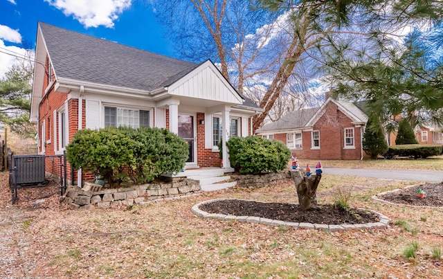 view of front of house with roof with shingles, central AC unit, and brick siding