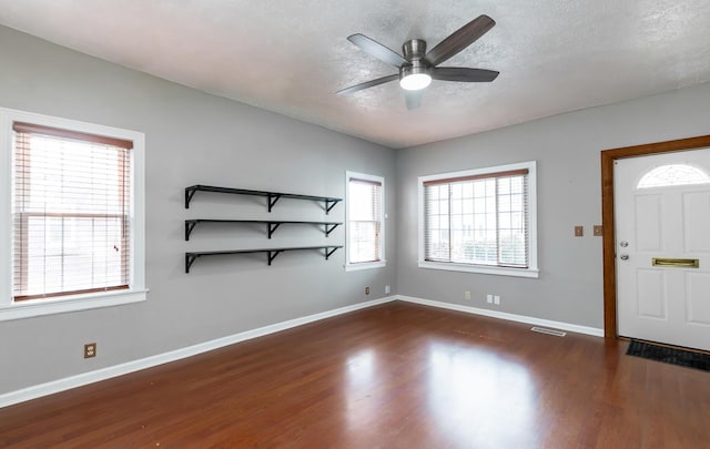 entryway with visible vents, a ceiling fan, a textured ceiling, wood finished floors, and baseboards