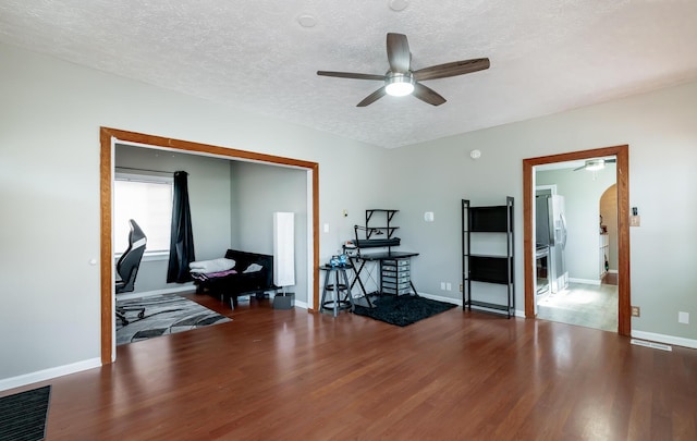 interior space featuring visible vents, ceiling fan, a textured ceiling, wood finished floors, and baseboards