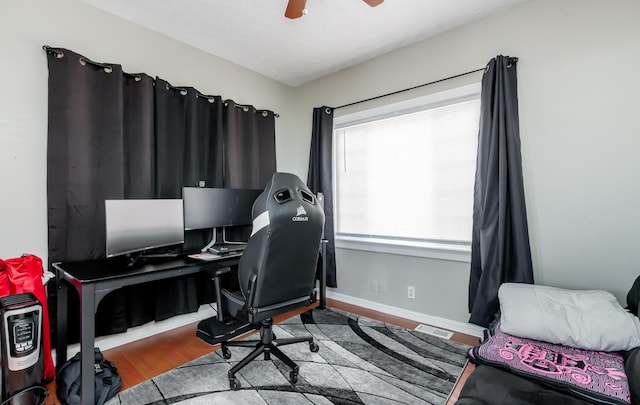 home office featuring visible vents, ceiling fan, baseboards, and wood finished floors