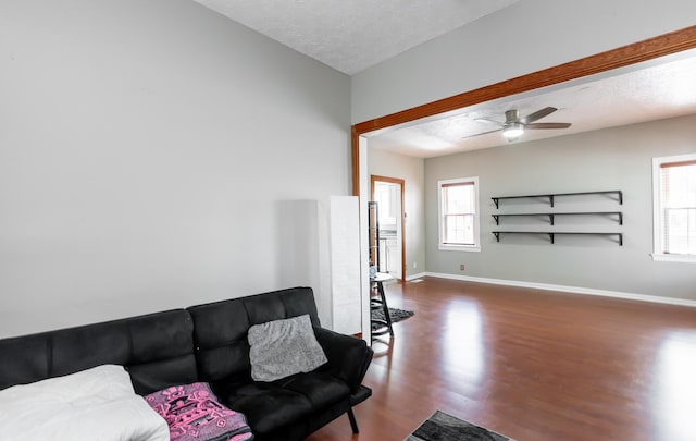 living room with a healthy amount of sunlight, a textured ceiling, baseboards, and wood finished floors