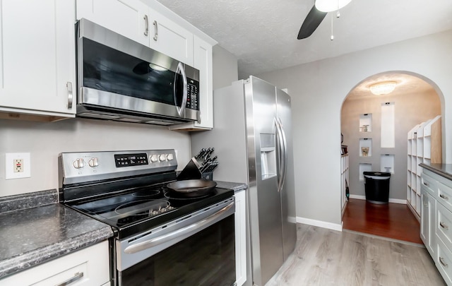 kitchen featuring a textured ceiling, ceiling fan, light wood-style flooring, stainless steel appliances, and white cabinets