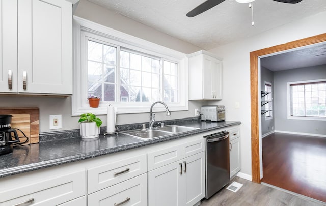 kitchen with white cabinets, dishwasher, wood finished floors, a textured ceiling, and a sink