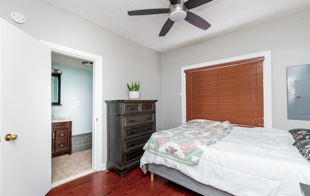 bedroom with ceiling fan, ensuite bath, wood finished floors, and electric panel