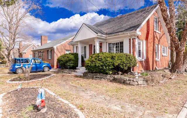 view of side of property with a shingled roof and brick siding