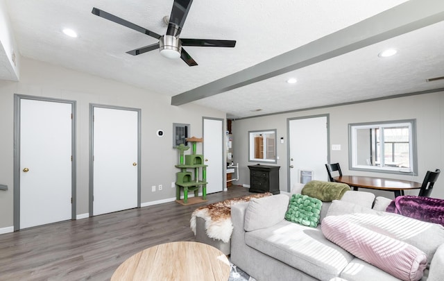 living room with lofted ceiling with beams, ceiling fan, wood finished floors, a textured ceiling, and recessed lighting