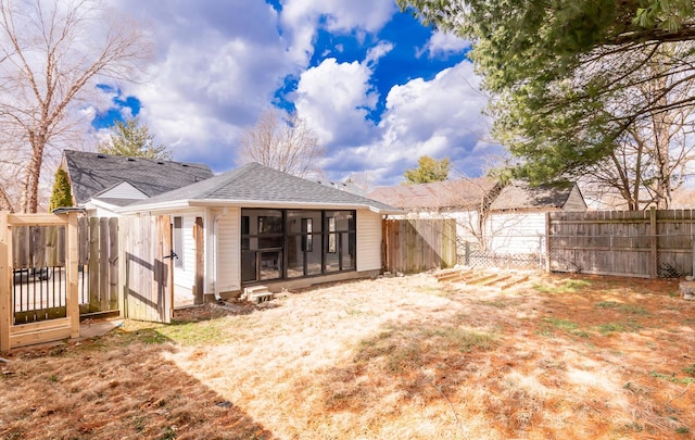 rear view of property featuring a shingled roof and a fenced backyard