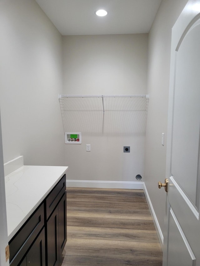 clothes washing area with hookup for an electric dryer, laundry area, washer hookup, wood finished floors, and baseboards